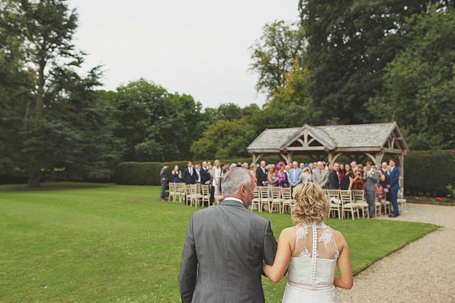 Bride walking with father toward outdoor wedding ceremony