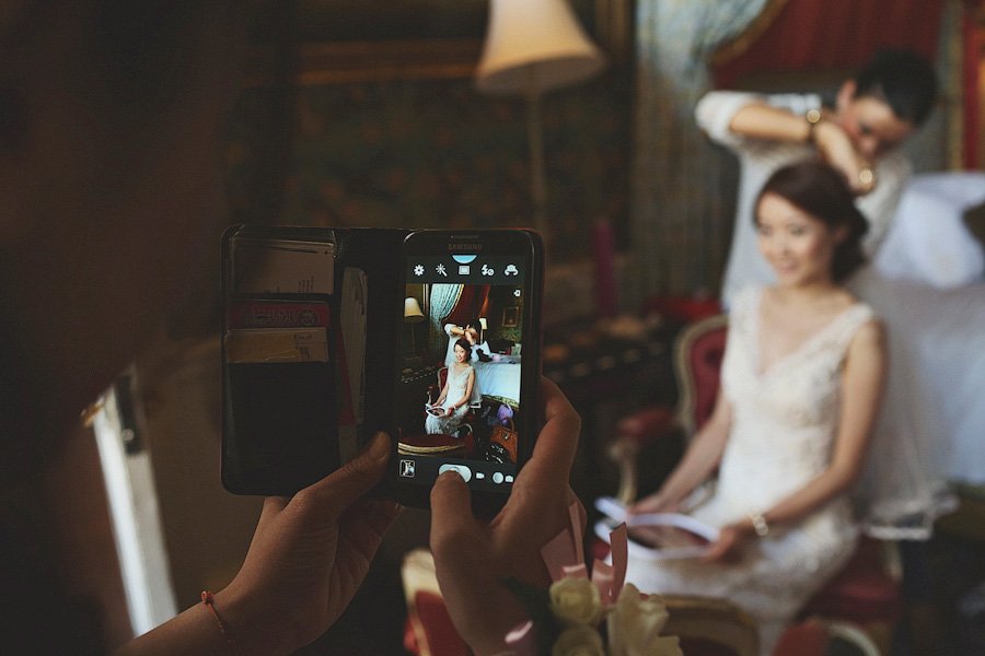 Photographer capturing bride getting hair styled indoors