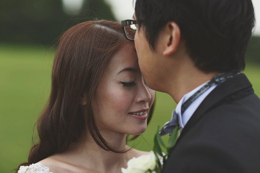 Groom kissing bride's forehead outdoors