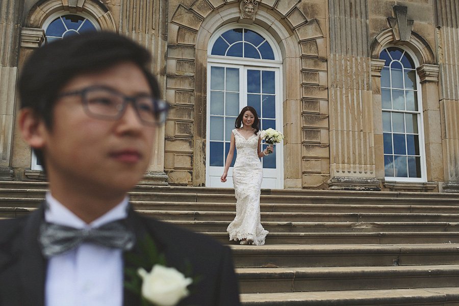 Bride descending steps of historic building with bouquet