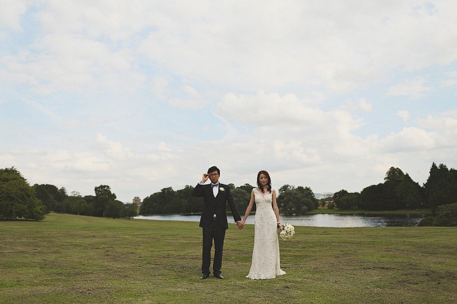 Bride and groom holding hands by lakeside