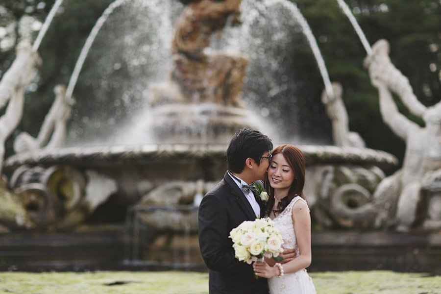 Bride and groom embracing before ornate fountain