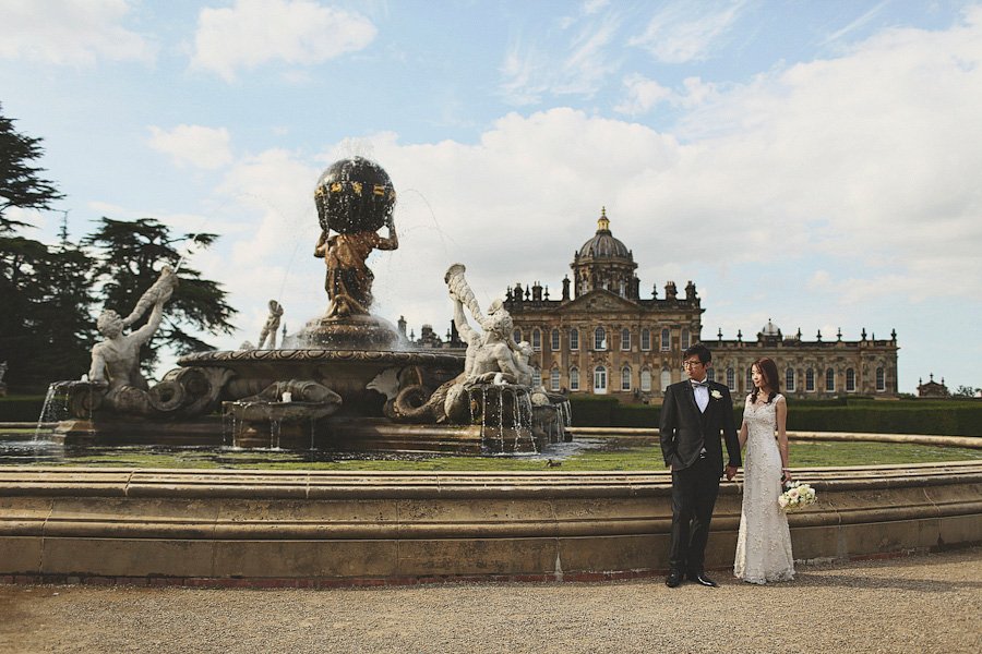 Bride and groom by ornate fountain and mansion