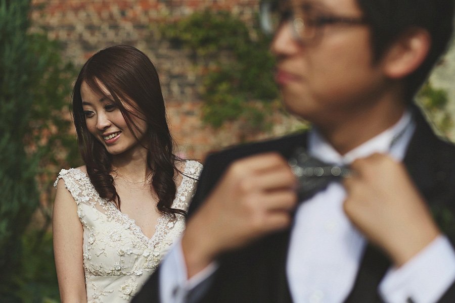 Bride smiling as groom adjusts bow tie