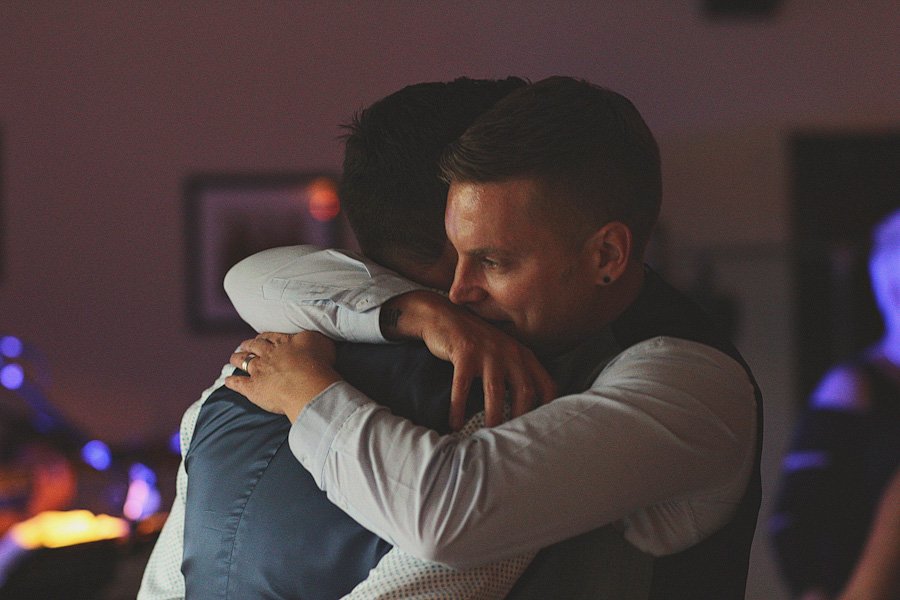 Two men sharing an emotional hug indoors