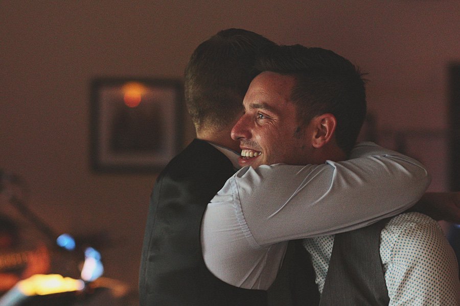Two men warmly embracing at indoor event