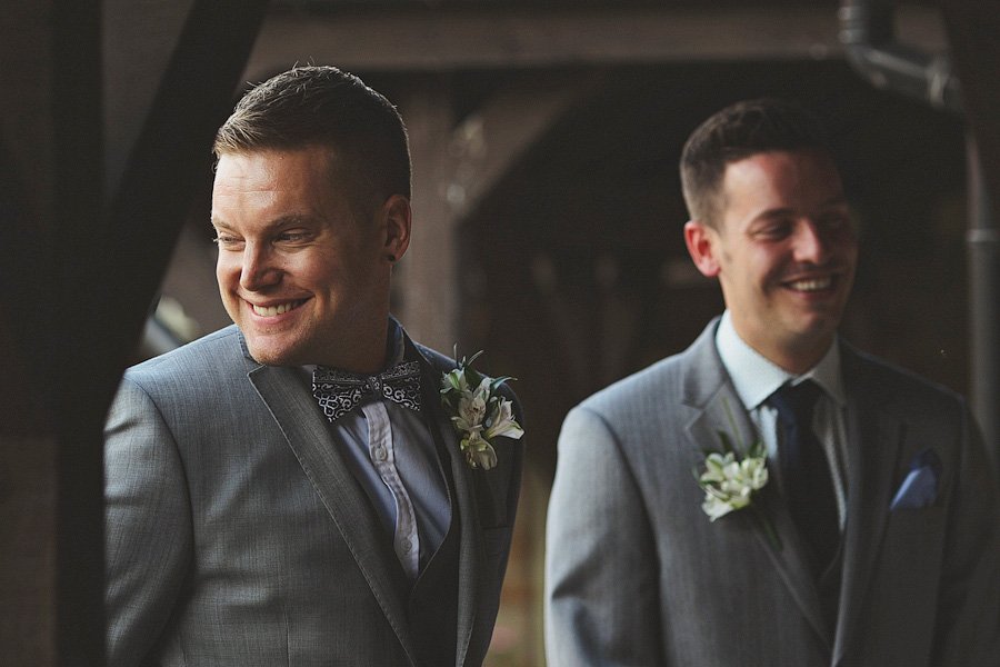 Two men in suits with boutonnieres smiling