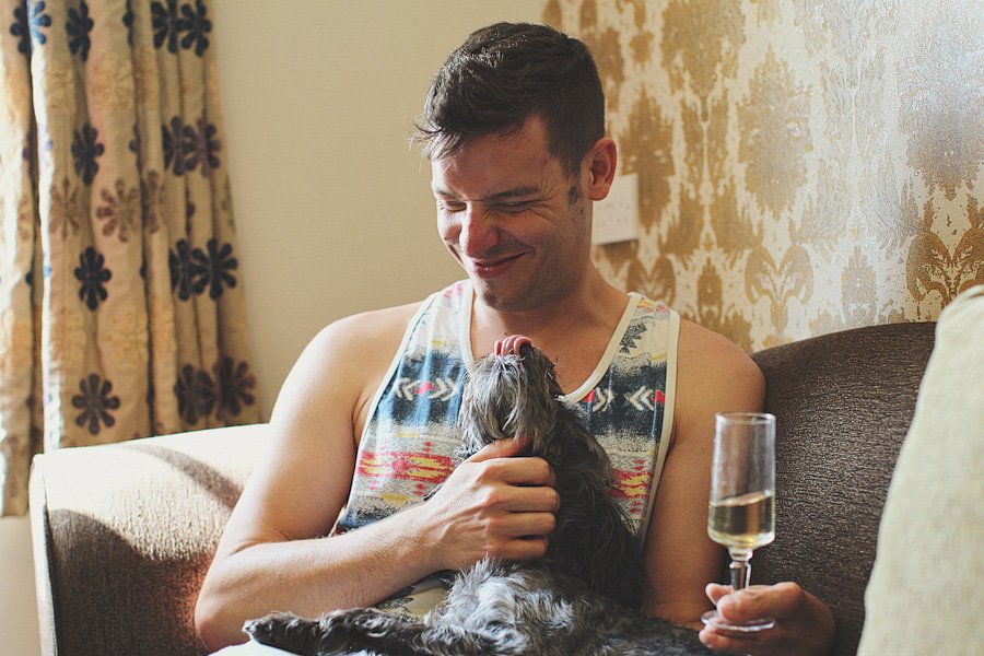 Man cuddling small dog on couch indoors