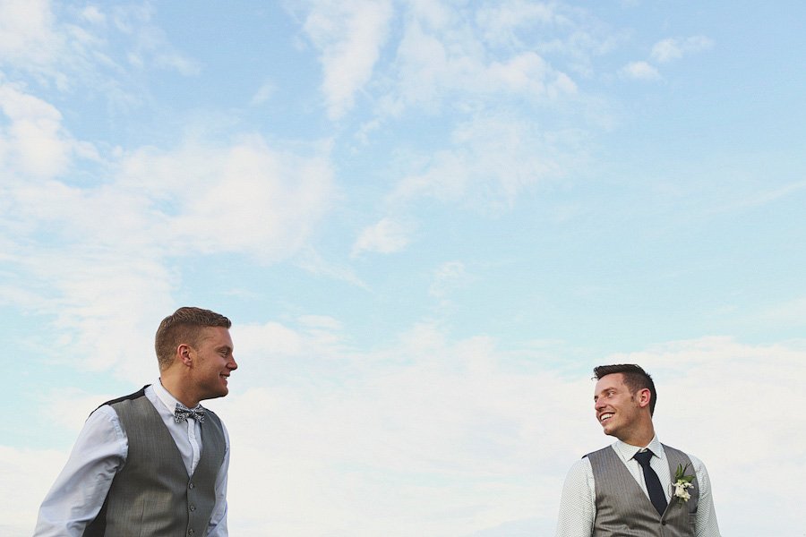 Two men in formal vests smiling outdoors