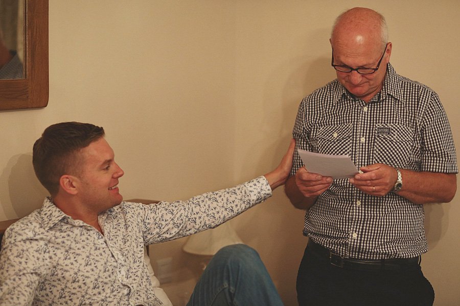 Older man reading letter beside younger man