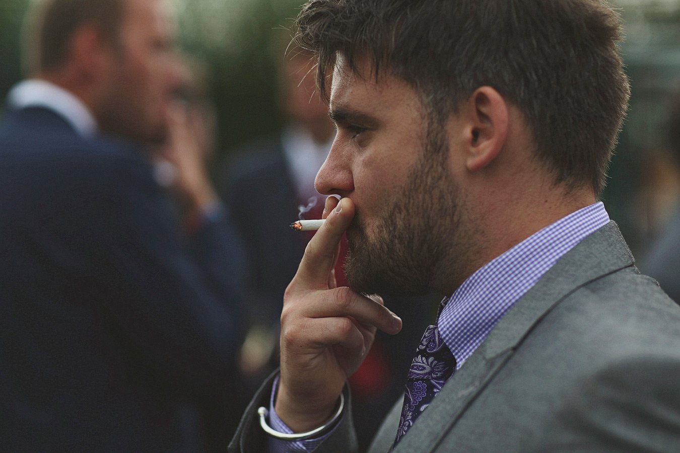 Man in suit smoking a cigarette outdoors