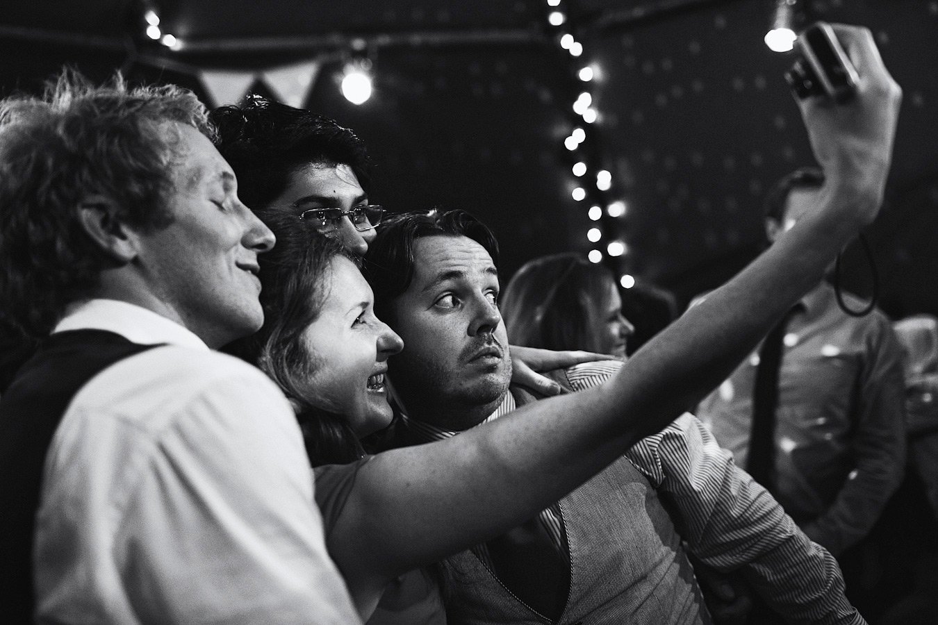 Friends taking selfie at party with string lights
