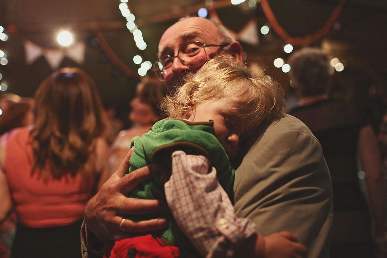 Older man hugging sleeping child at party