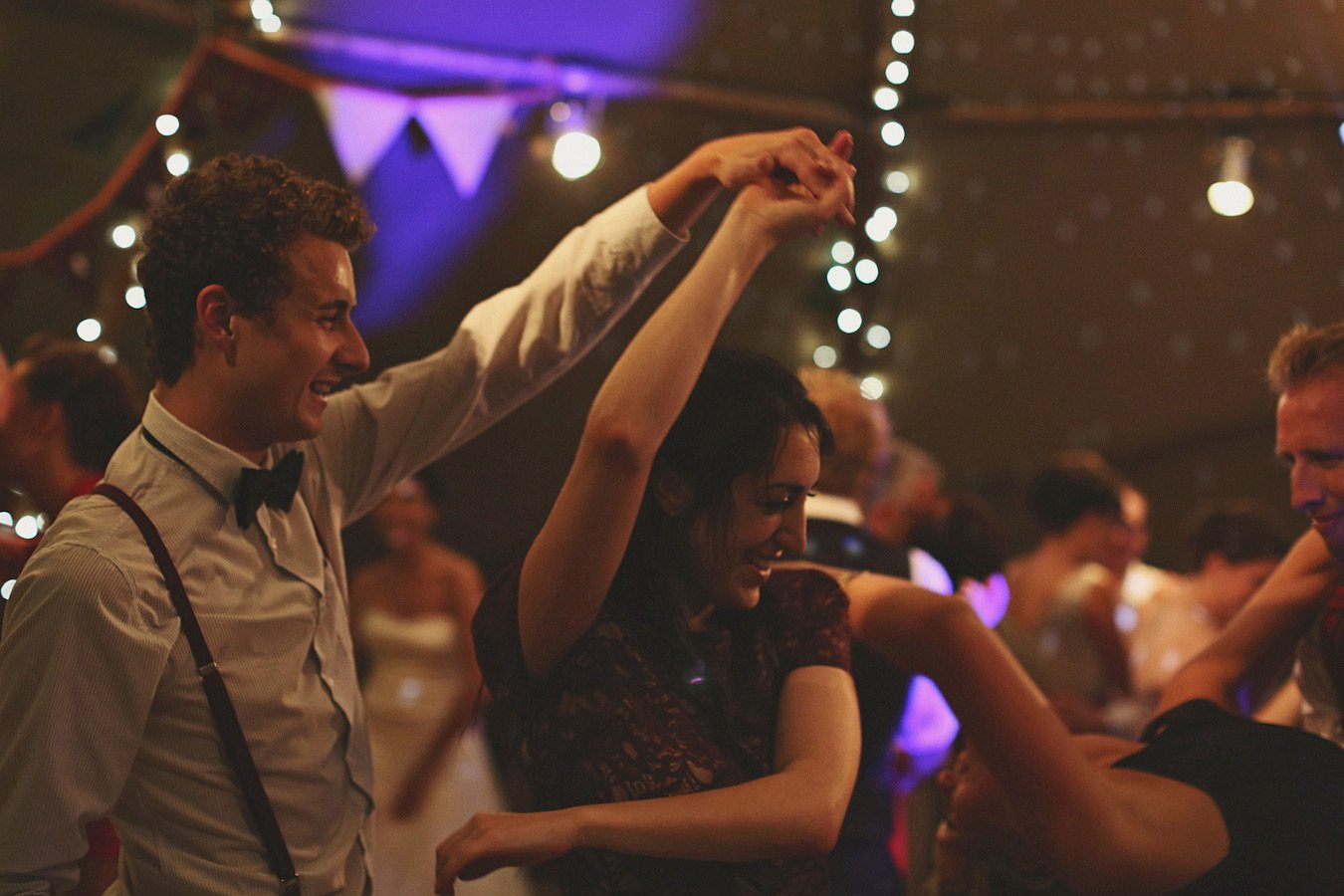 Couple dancing at festive party with string lights