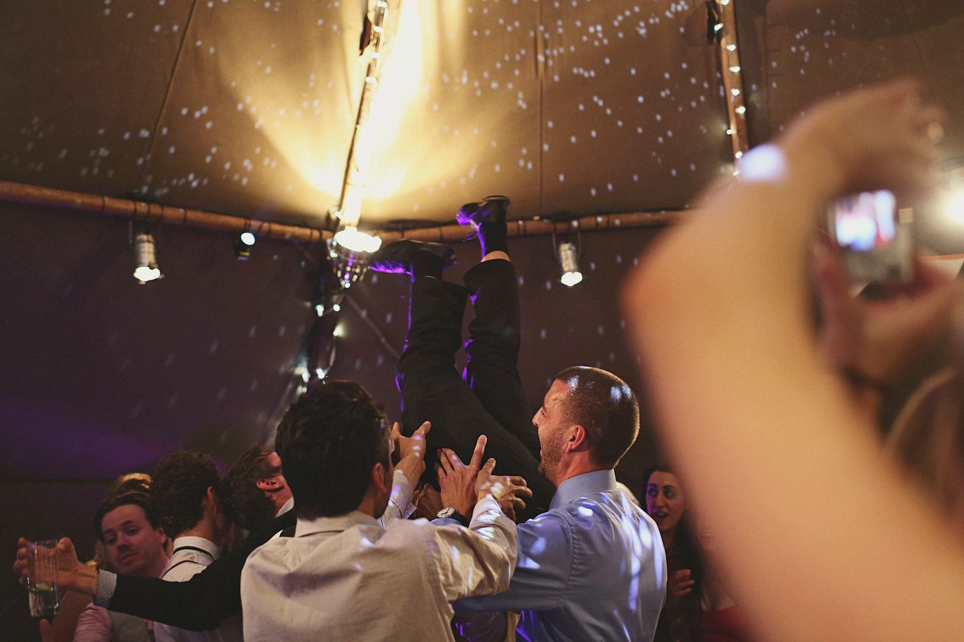 Guests lifting man upside down at party