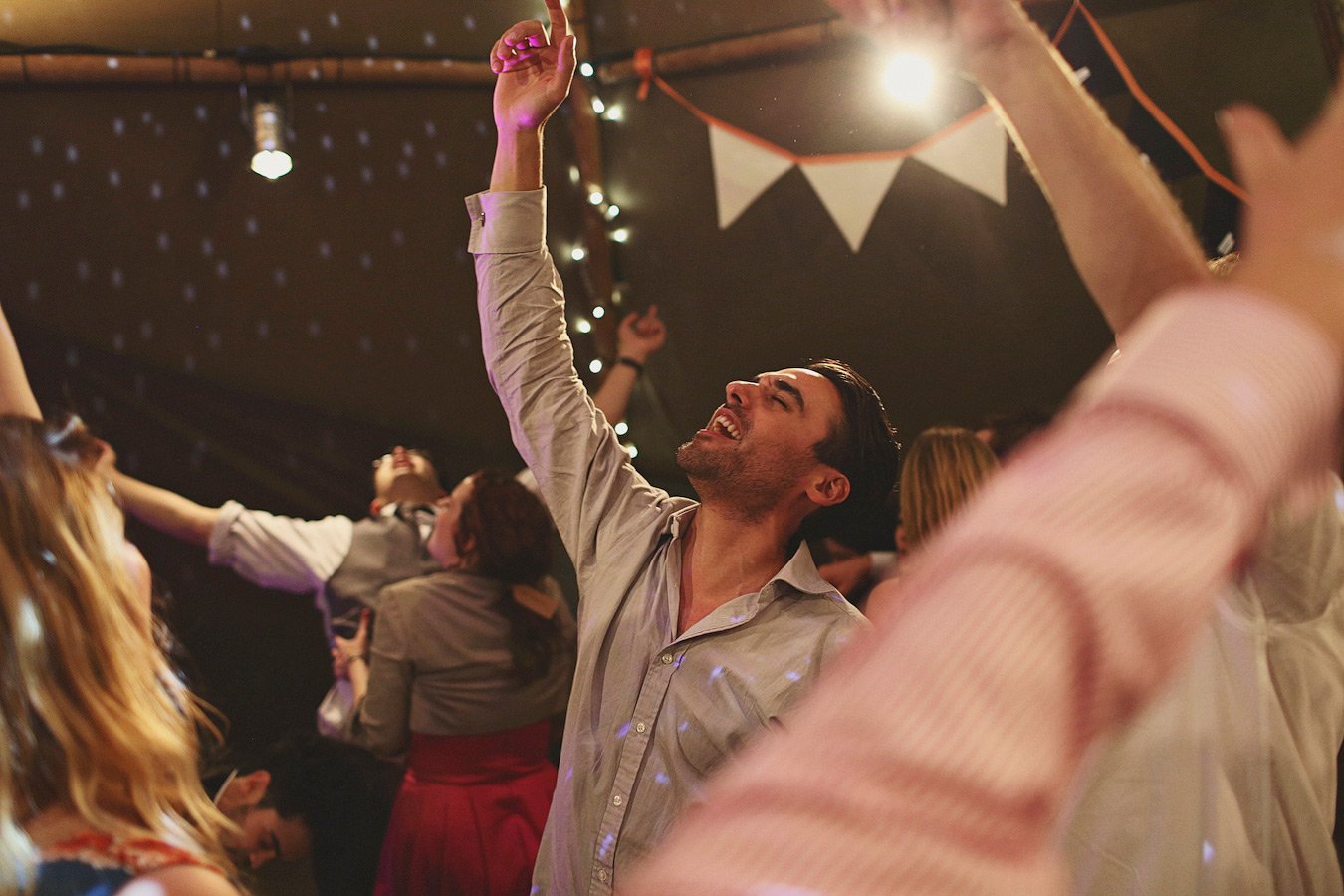 Friends dancing joyfully at indoor party with lights