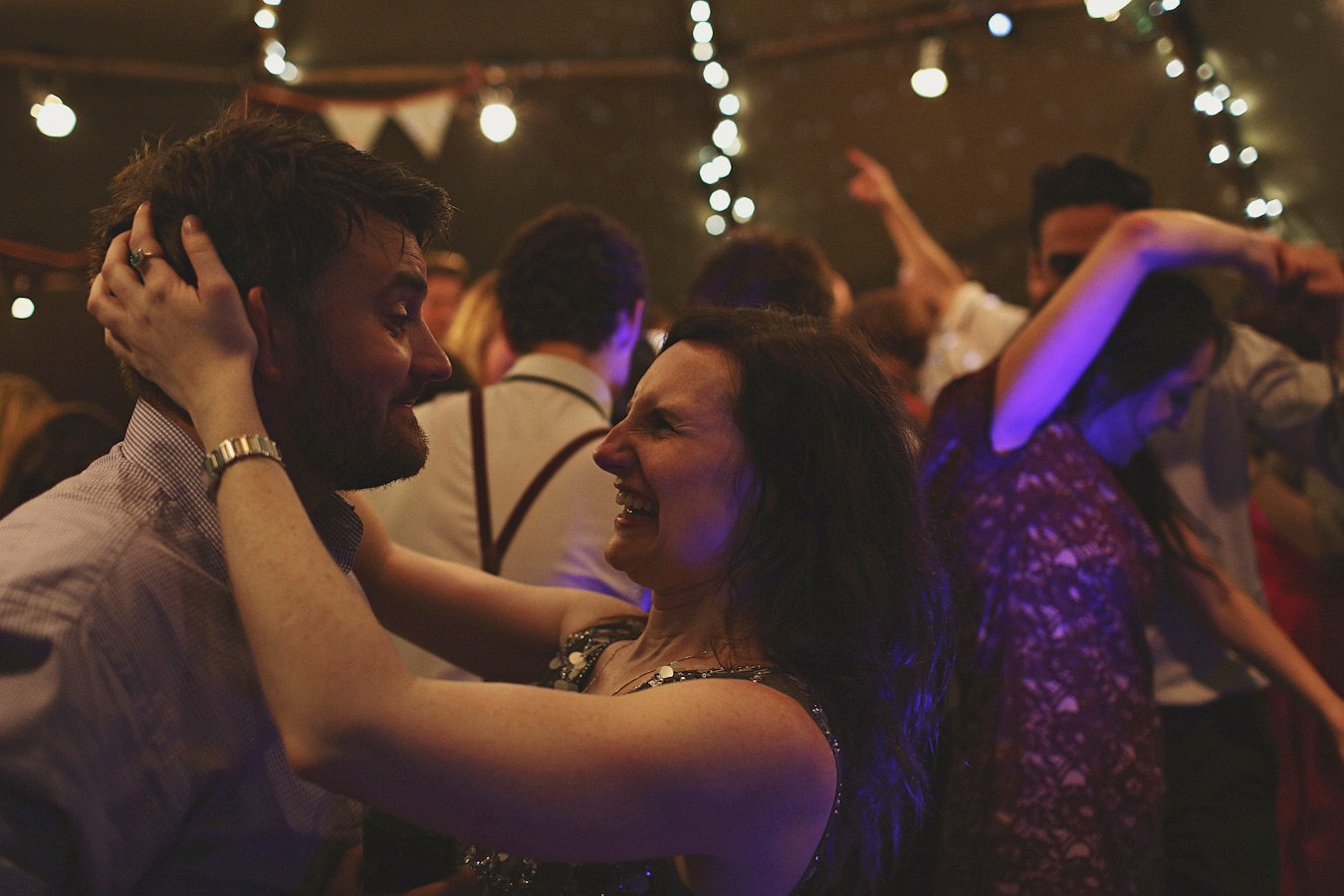 Couple dancing joyfully under string lights
