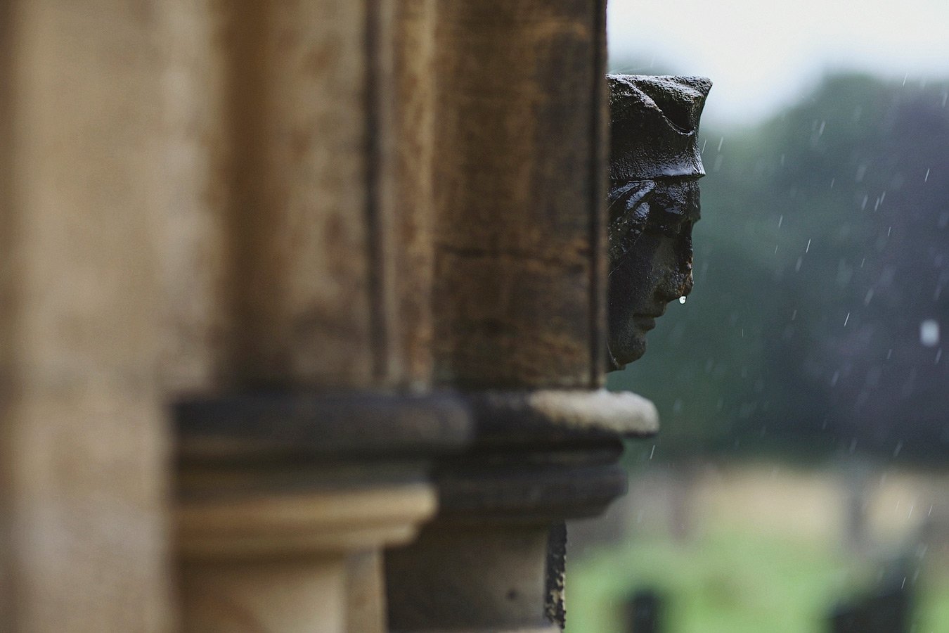 Stone face carving in rain on column