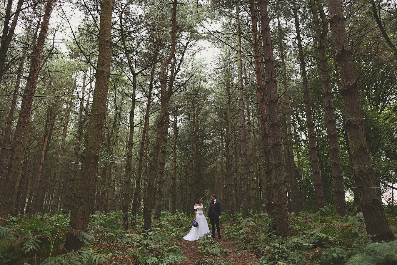 Bride and groom standing in forest clearing