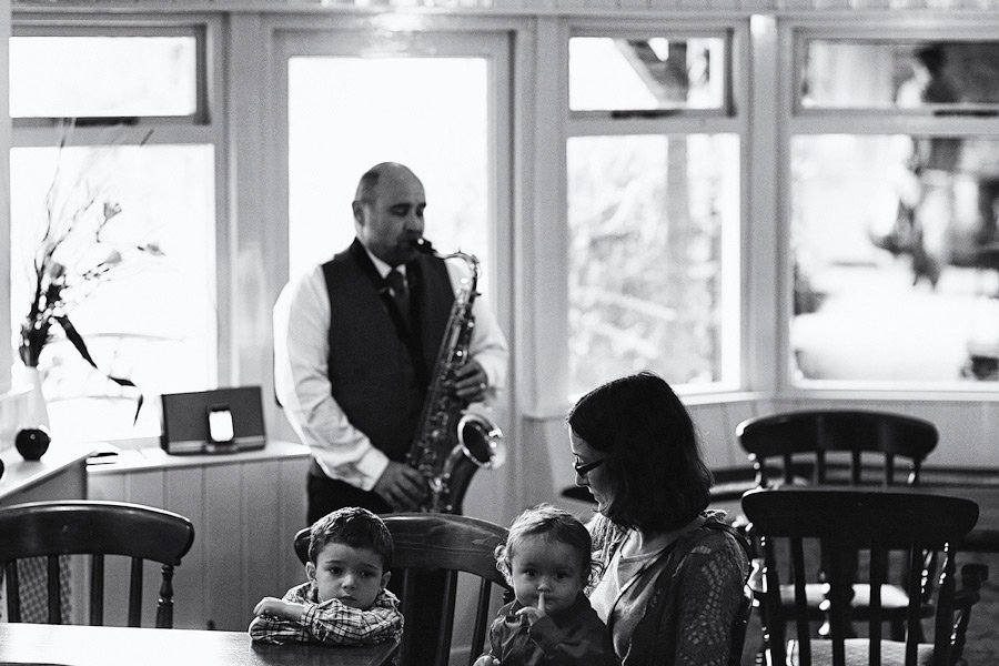 Man playing saxophone for woman and children indoors