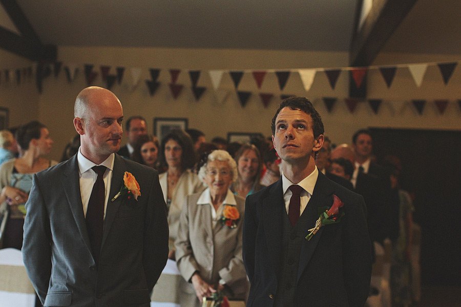 Two grooms standing at indoor wedding ceremony