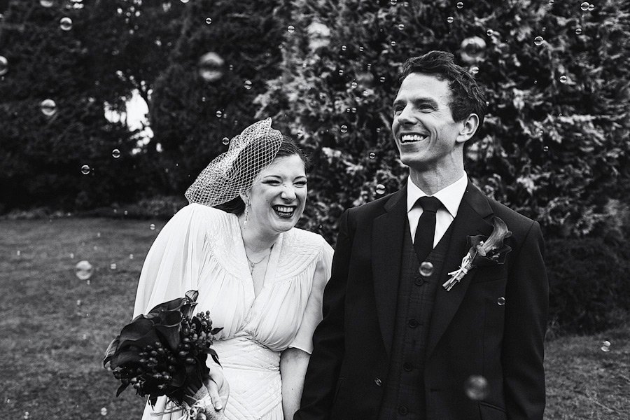 Bride and groom laughing outdoors with bubbles