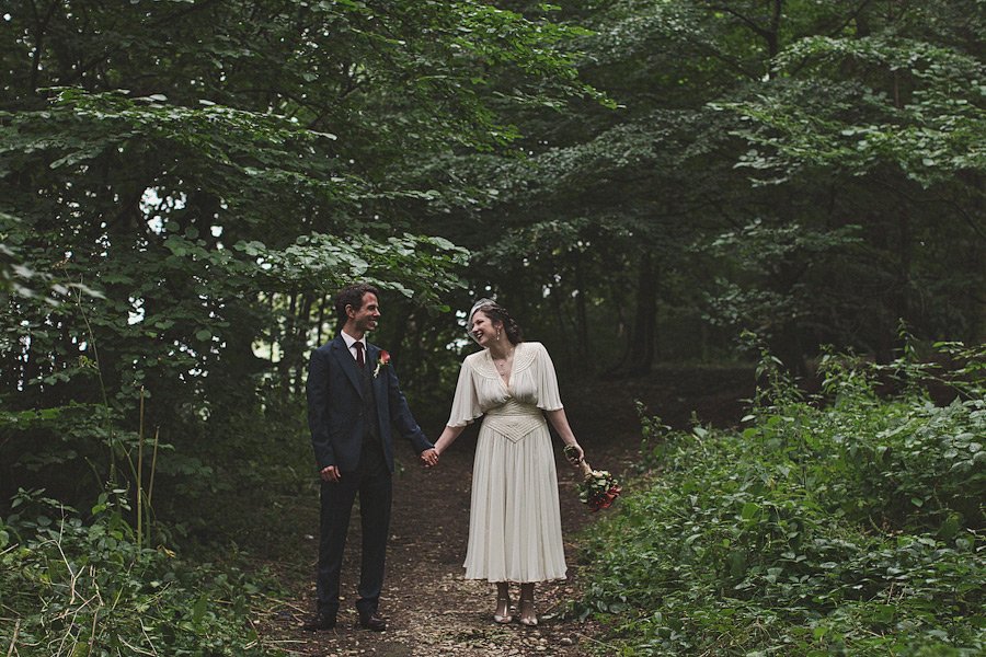 Bride and groom holding hands in forest