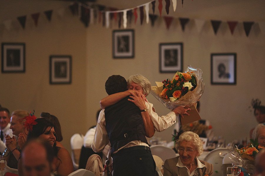 Man hugging older woman holding bouquet at celebration