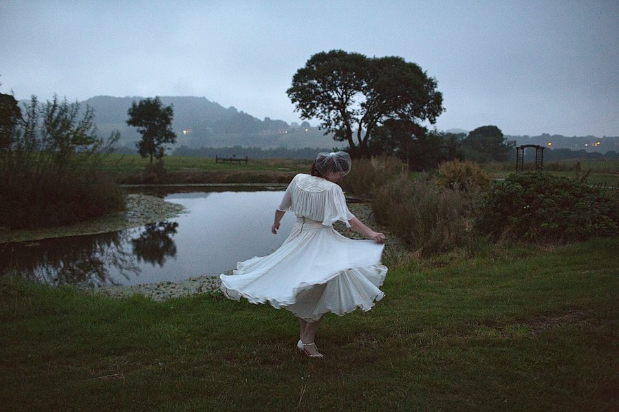 Woman in white dress twirling by pond