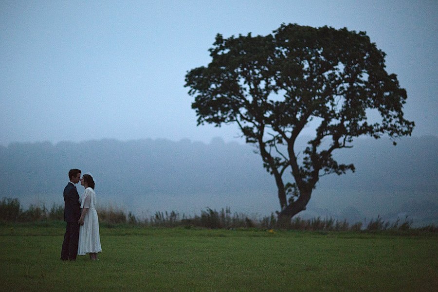 Couple standing near tree at dusk