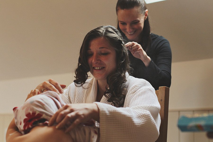 Woman holding baby while getting hair styled