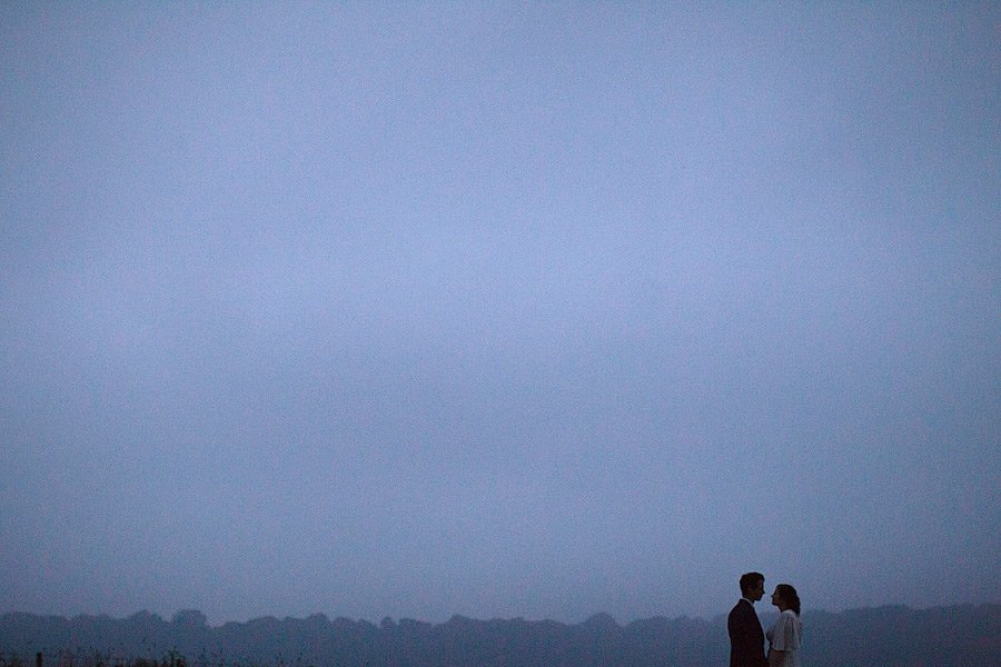 Silhouetted couple standing beneath vast evening sky