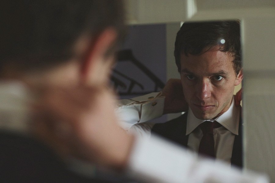 Man adjusting tie in mirror reflection
