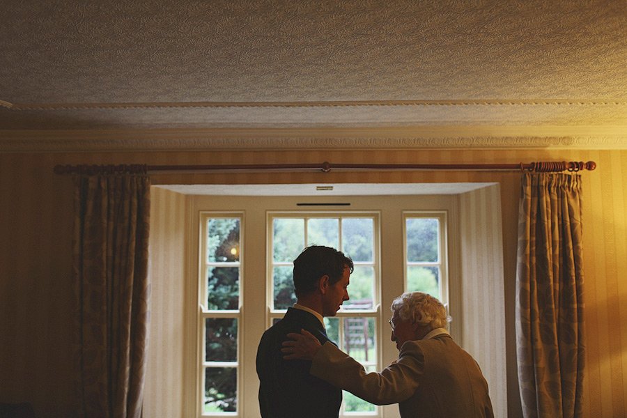 Elderly person comforting younger man by window