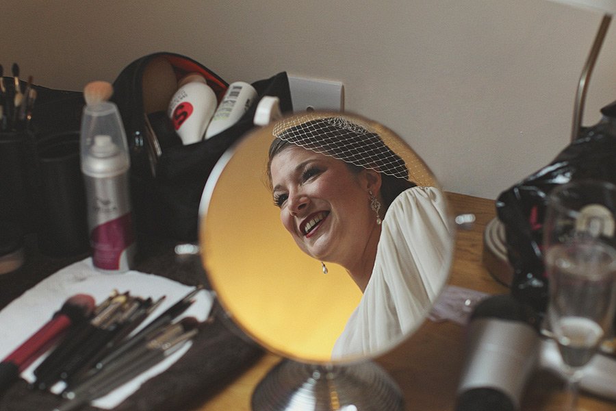 Bride smiling in vanity mirror reflection