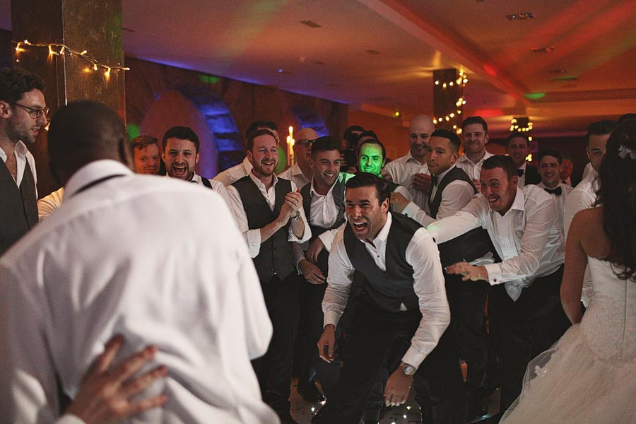 Groom surrounded by cheering groomsmen at reception