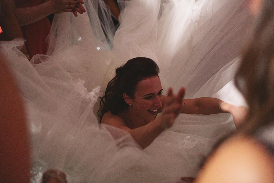 Bride laughing beneath flowing wedding dress fabric