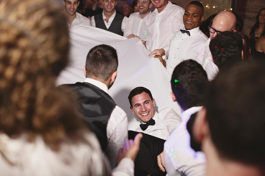 Groom lifted on chair during wedding celebration