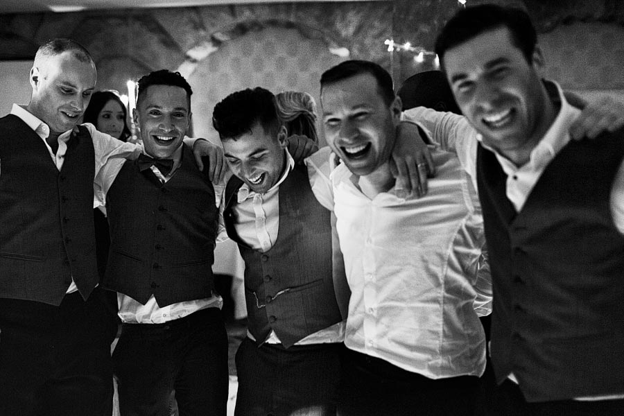 Five men laughing together at wedding reception