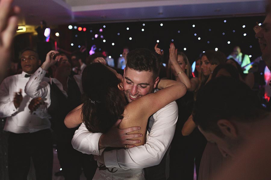 Couple hugging on crowded dance floor at party