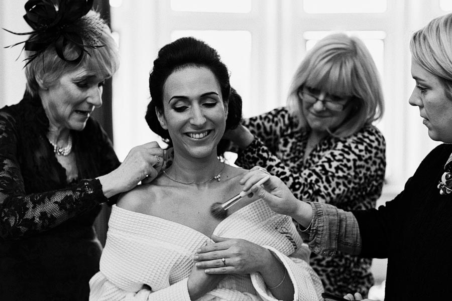 Bride getting ready with makeup and jewelry assistance