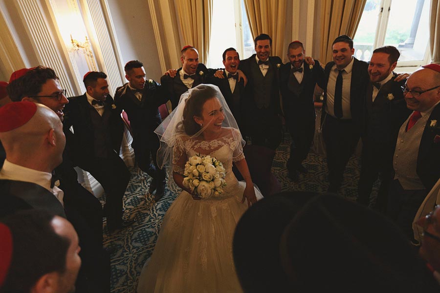 Bride surrounded by groomsmen indoors on wedding day