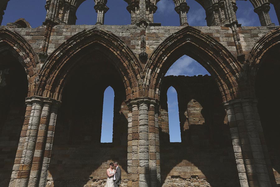 Couple beneath Gothic stone arches in historic ruins