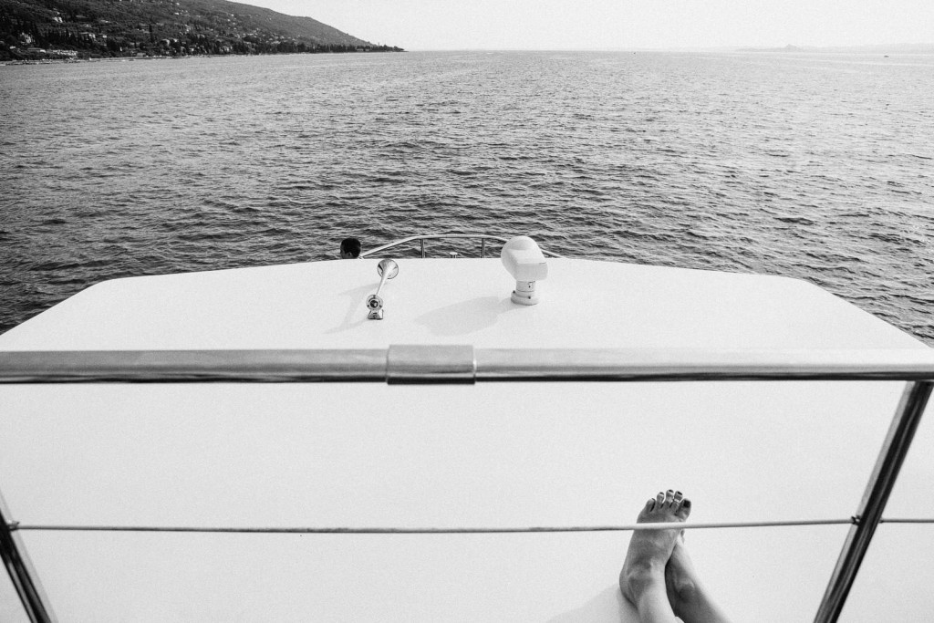 Bare feet resting on boat deck as coastline drifts by, quiet wedding day moment at sea.