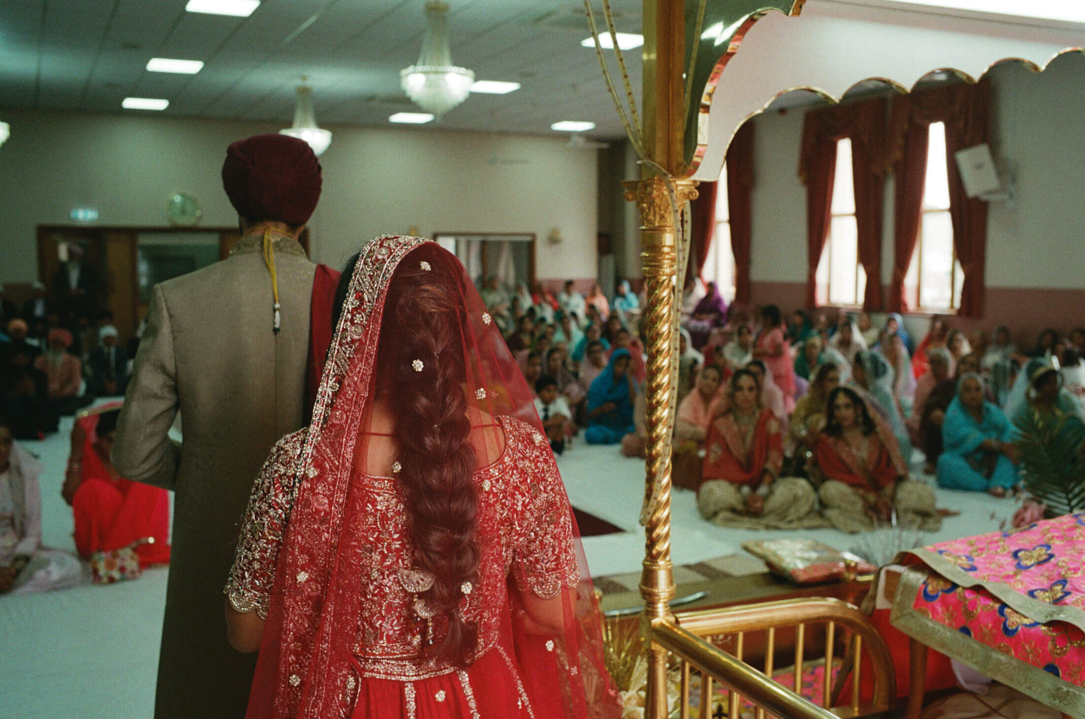 Sikh bride in a red veil is led by the groom ahead during Laavaan