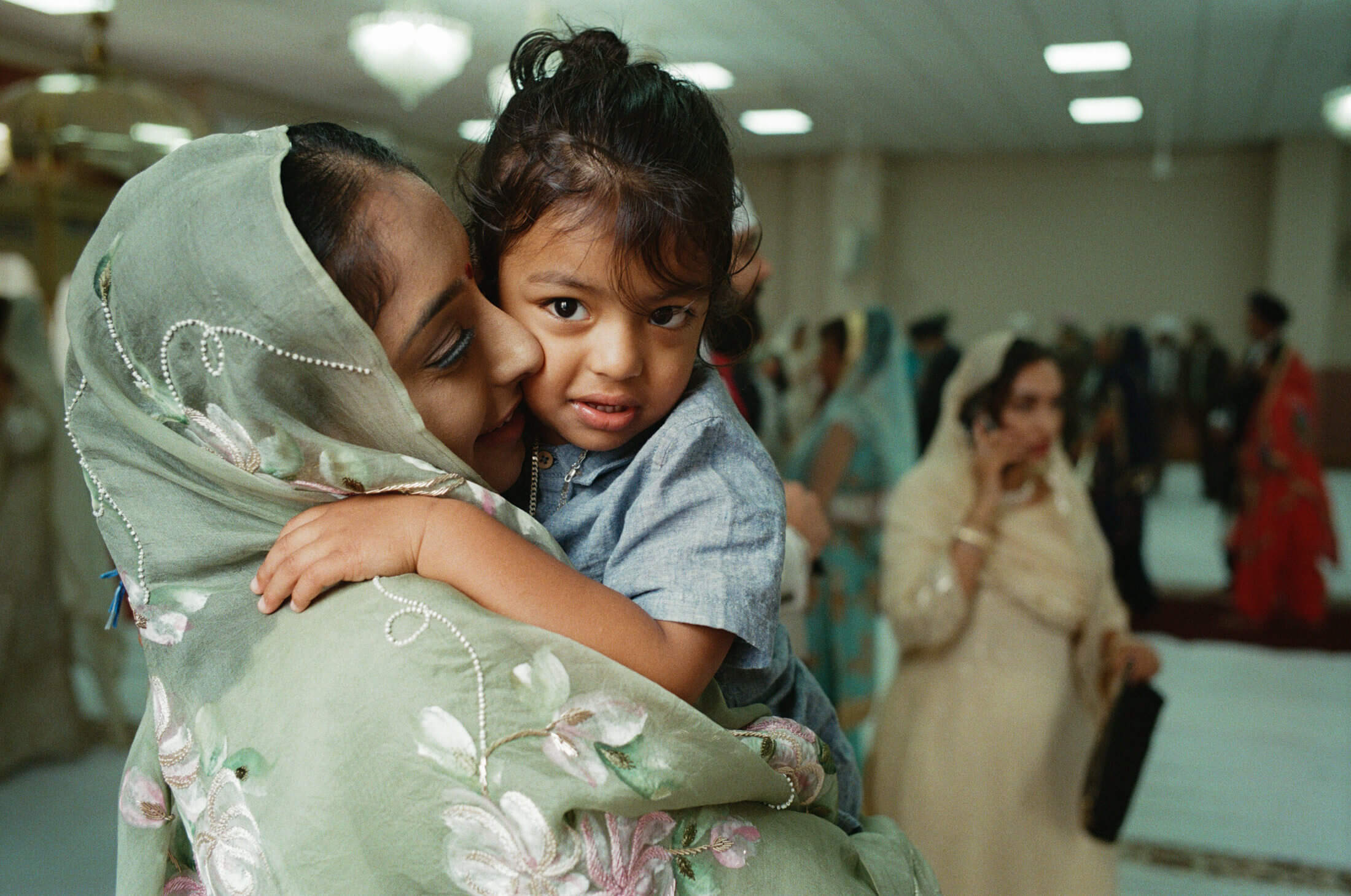Woman kissing a young child on the cheek during a Sikh wedding celebration