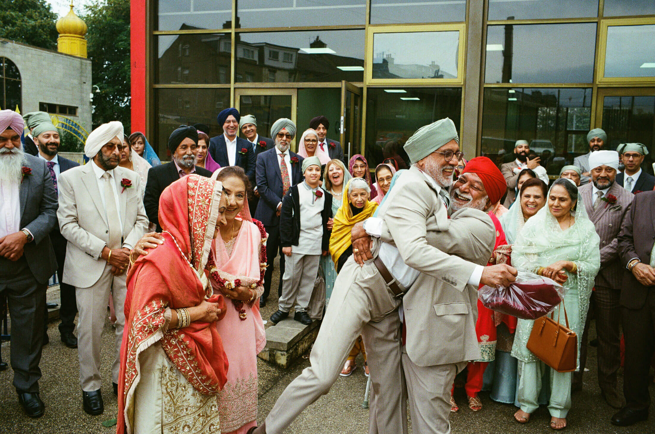 Sikh wedding guests laughing and embracing outside the gurdwara