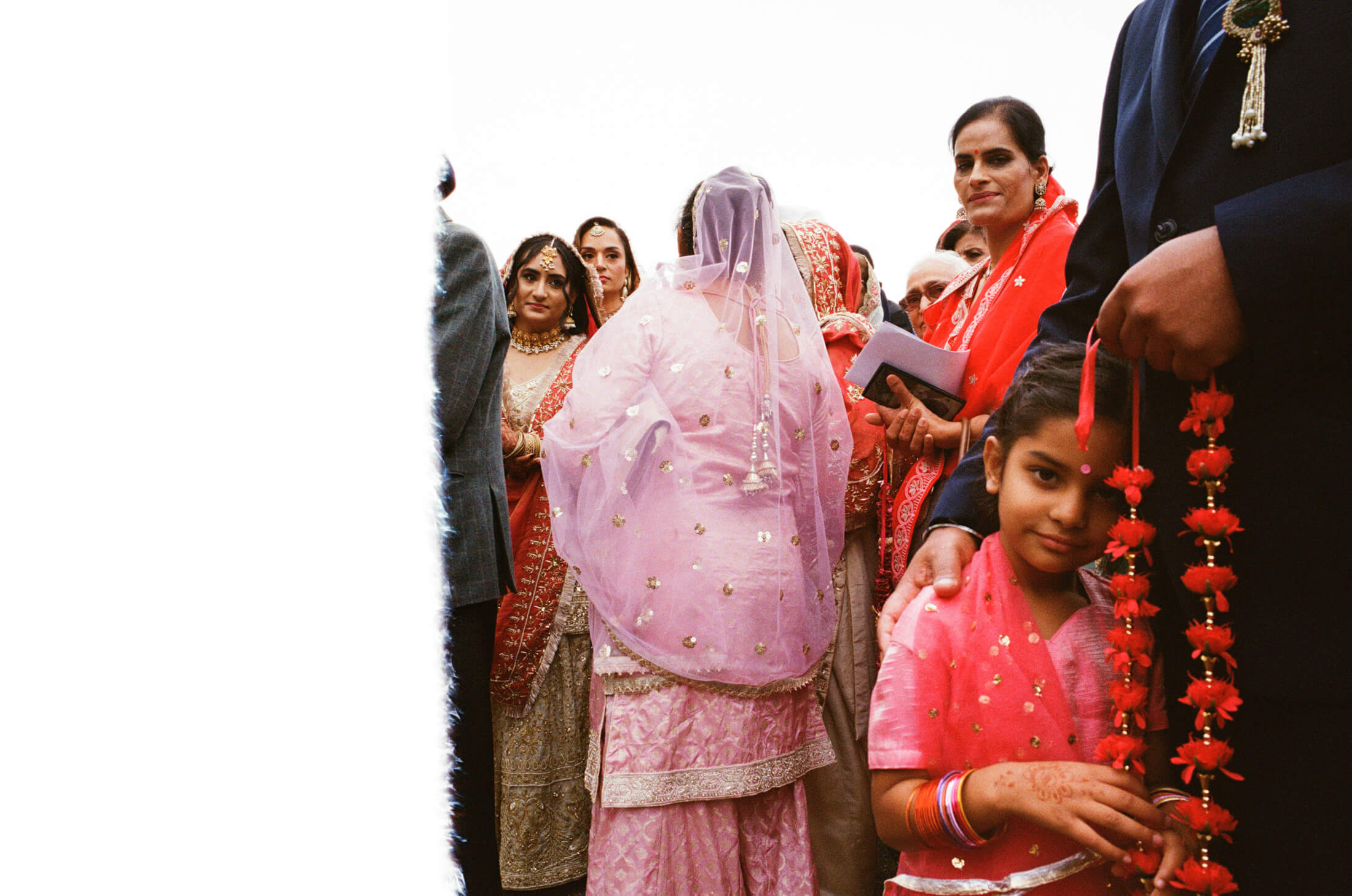Women in pink and red traditional outfits gathered outside during a Sikh wedding