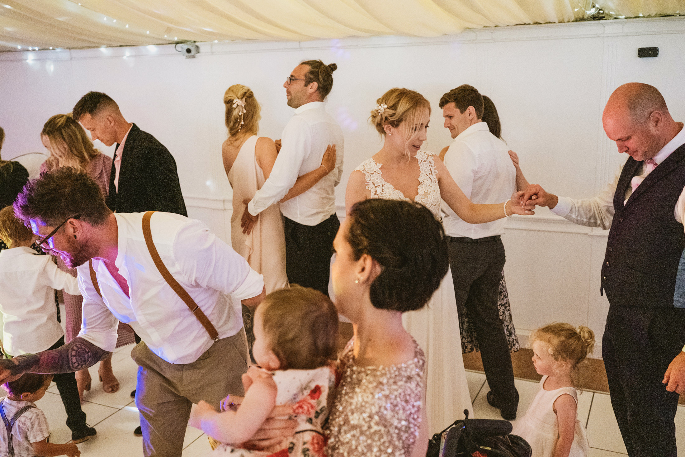Guests dancing at lively wedding reception.