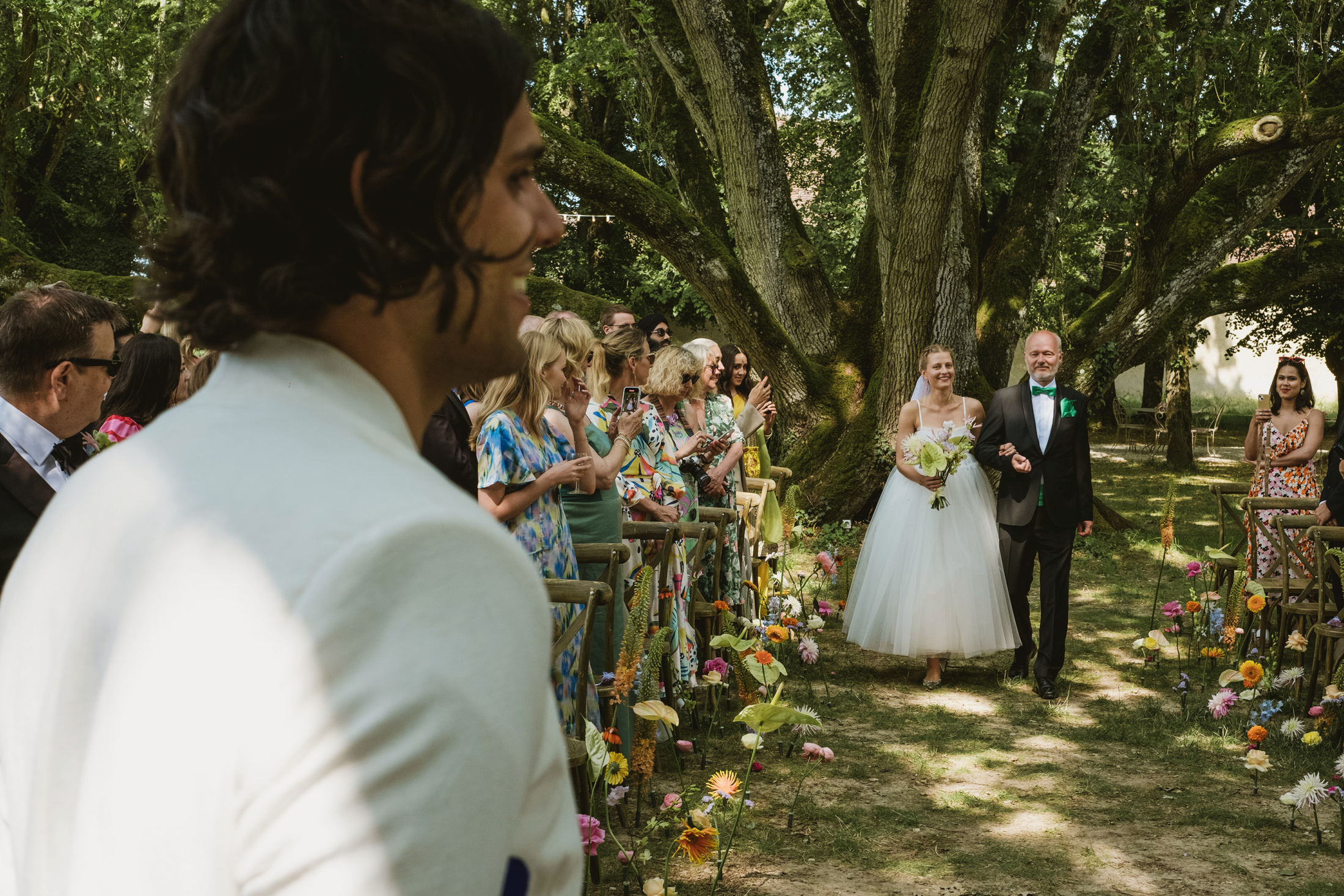 The groom sees the bride for the first time as she walks down the aisle at Chateau du Fey in France